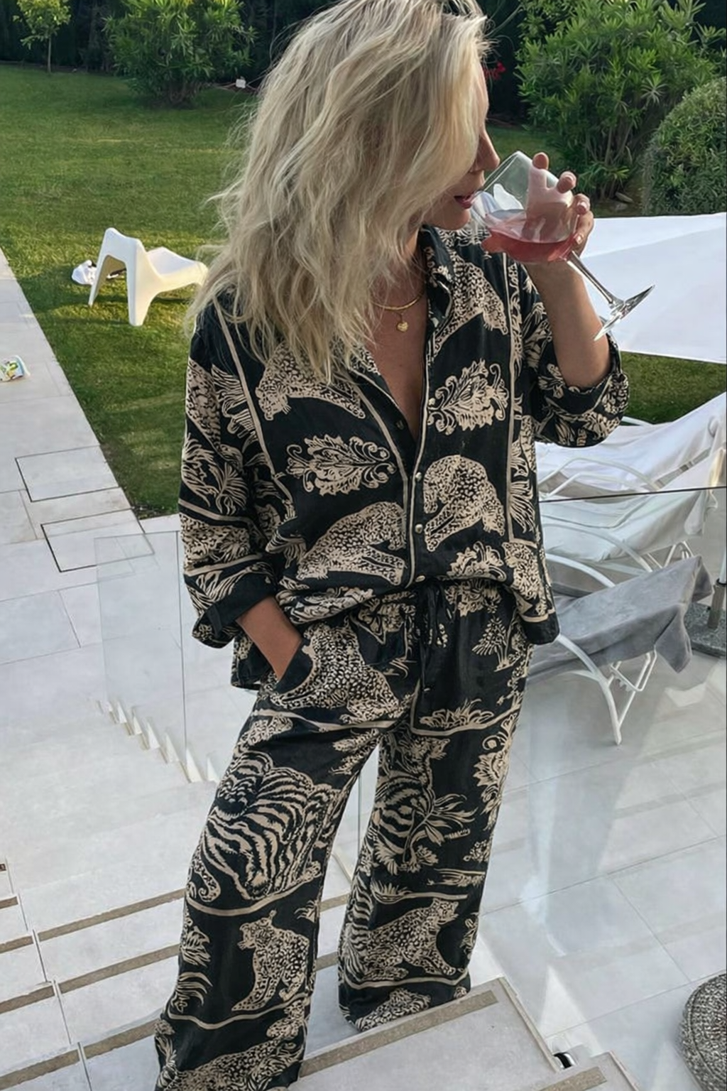 Kadın, doğal boyalı hayvan desenli el blok baskı pijama takımı giyiyor, bahçede şarap içiyor