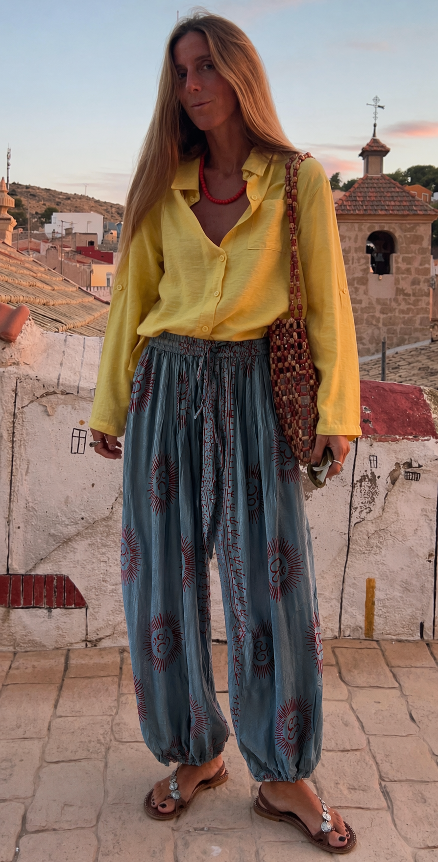 Sarı elbise ve el baskı desenli mavi pantolon giyen kadın, doğal malzemelerle üretilmiş boho tarzı giyim
